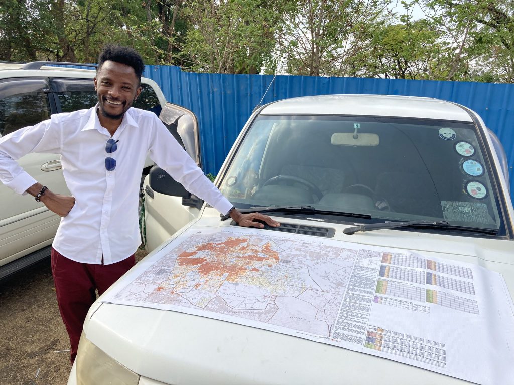 GRID3 consultant Chisenga Musuka with printed microplanning map used by Ministry of Health EPI teams for vaccination planning, Lusaka, Zambia