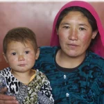 Photo of Mum-of-four Nekbakht, 25, holds her child as she waits for a health worker to administer polio vaccine drops