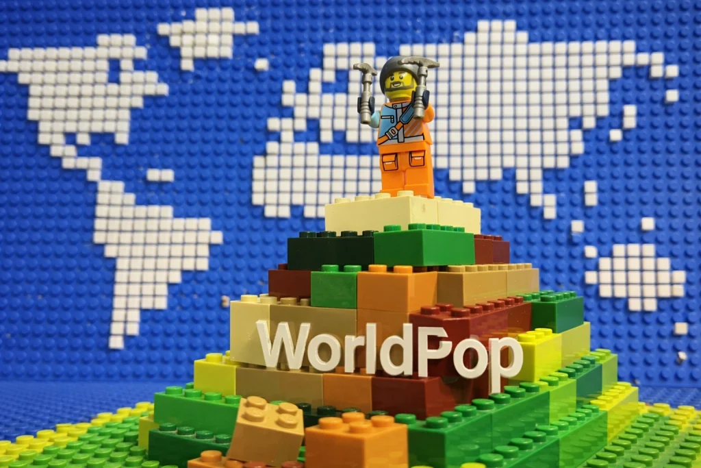 AI generated image of Lego minifigure on a brick mountain plus the WorldPop logo