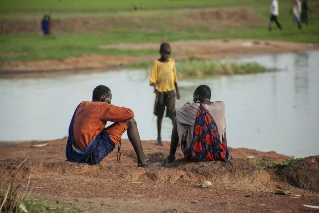 Photo of young men sitting close to a fishing river in South Sudan