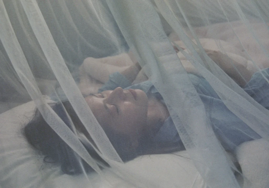 Photo of someone sleeping under mosquito net.