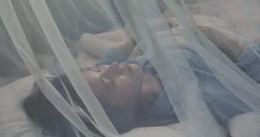 Photo of someone sleeping under mosquito net.
